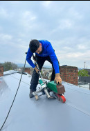 Motivierter Dachdecker bei der Herstellung von sauberen Abdichtungsarbeiten